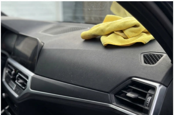 Close-up van een schoongemaakt Europees auto-dashboard, gele microvezeldoek ligt ernaast